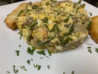 Scrambled eggs with mushrooms, prawns and young garlic